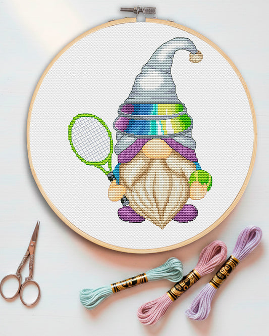 Embroidery hoop with a colorful gnome design, scissors, and embroidery threads on a light background