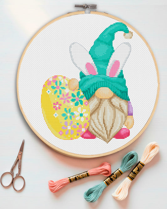 Cross stitch pattern of an Easter Gnome with bunny ears and a hen.